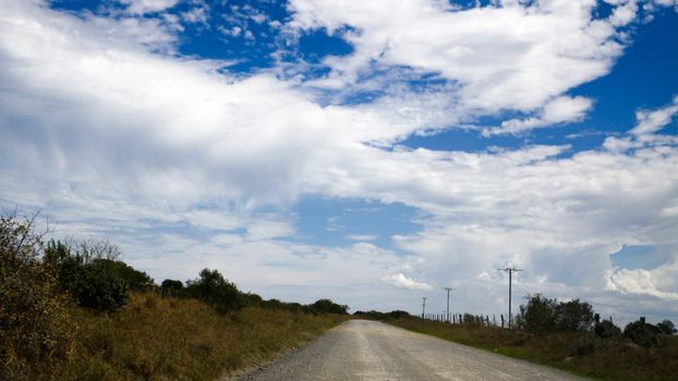 Dusty road with a hole in the clouds in the sky.