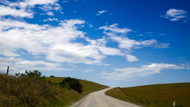 Dusty road with green grass on the sides.