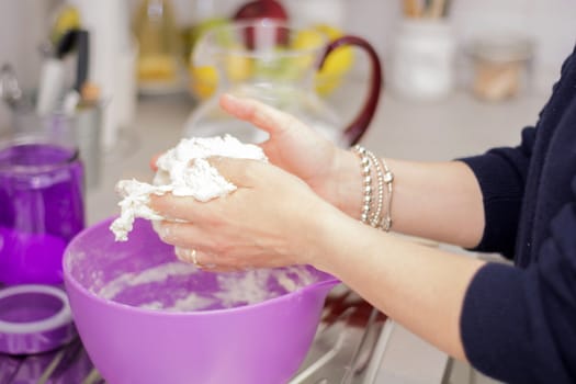 female hands in flour closeup kneading dough on table