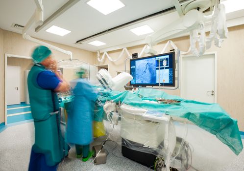 Blurred figures of surgeons during laparoscopic heart surgery in modern hospital.
