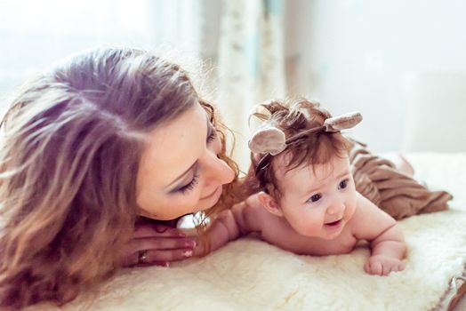 naked baby with mother lying on a white soft blanket