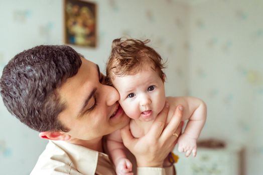happy father holds on hands naked baby in a room