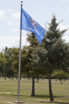 Oklahoma state flag waving against a blue sky