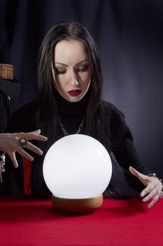 Fortune teller with a magic ball on a black background