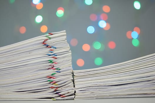 Pile of paperwork with colorful paperclip have colorful bokeh circle or defocused of glitter as background.