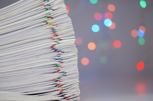 Stack of paperwork with colorful paperclip have colorful bokeh circle or defocused of glitter as background.