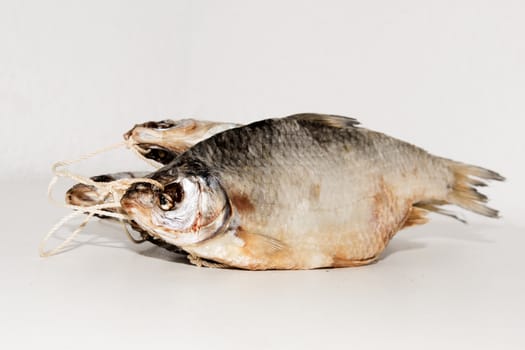 Dried fish on the table. Salty dry river fish on a white background. Dead dry salty fish - snack to beer. Isolated on white. .