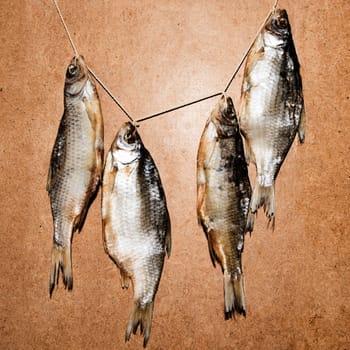 Dried fish on the table. Salty dry river fish on a wooden impressive background. Dead dry salty fish - snack to beer.  garland of salted and dried fish. dried fish hanging on a line, closeup. Dry fish on a wooden background. dried fish hanging on a rope, closeup.