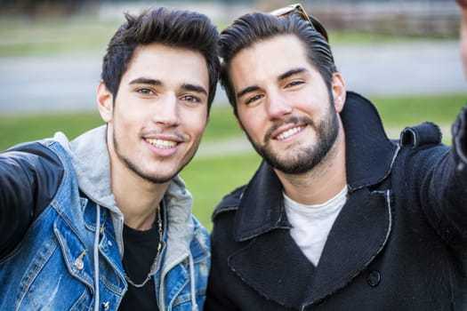 Two young men taking selfie while outdoors, point of view of the camera itself