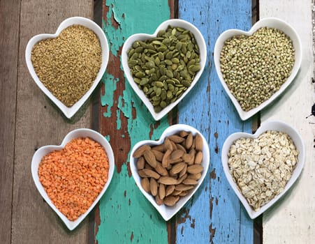 Background of cereals food in heart shaped bowls set on old vintage wooden texture.