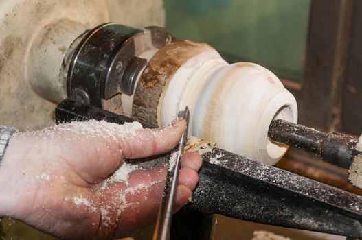 Master slowly carving chisel candlestick on a lathe