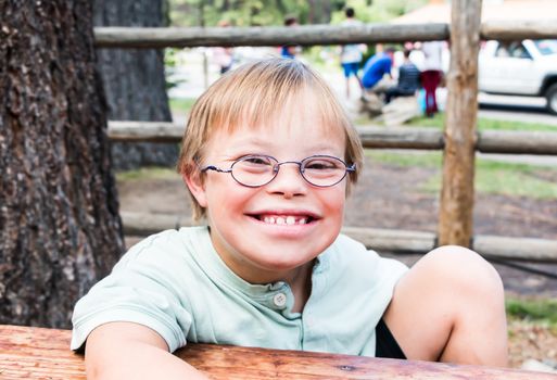 Cut Little Boy With Downs Syndrome Sitting at Table