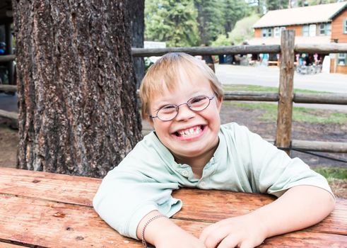 Cut Little Boy With Downs Syndrome Sitting at Table