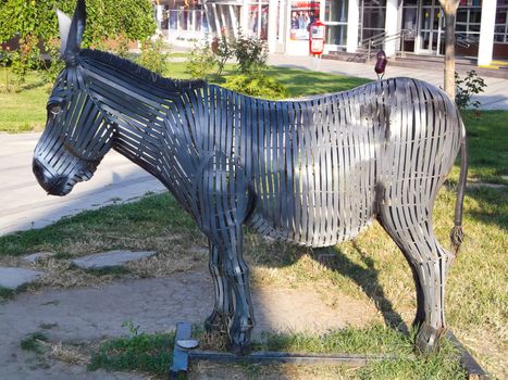 sculpture of a donkey made of metal presented in the open air