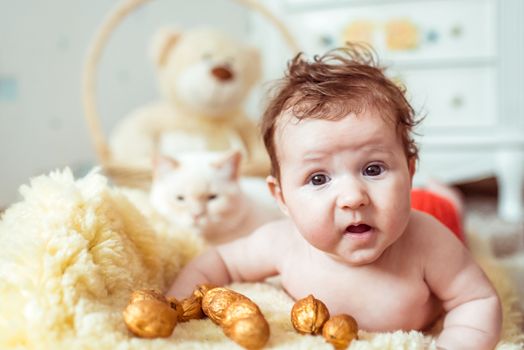 naked baby lying on a yellow soft blanket with decorated golden nuts in the room