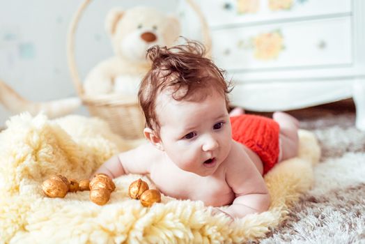 naked baby lying on a yellow soft blanket with decorated golden nuts in the room