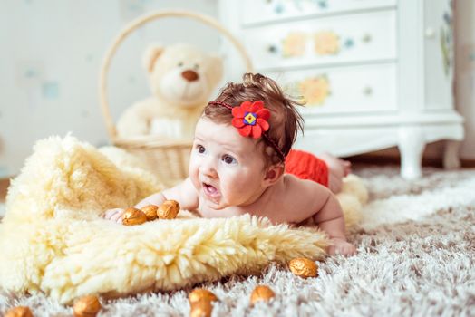 naked baby lying on a yellow soft blanket with decorated golden nuts in the room