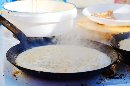 Pancake fried on a hot frying pan, steam pan over