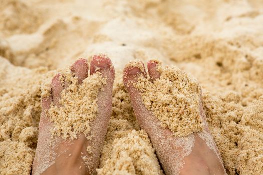 Holiday concept. Woman feet close-up relaxing on beach, enjoying sun