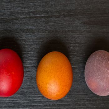 Colorful Easter eggs on dark wooden background.