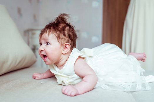 baby in white dress lying on the bed in the room