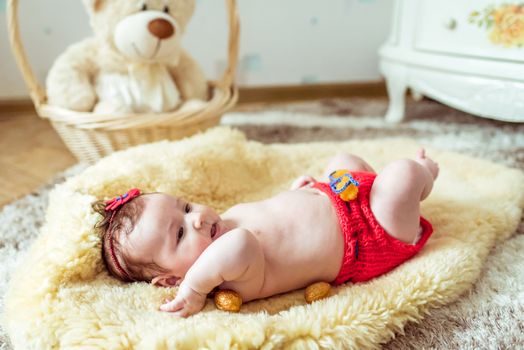 naked baby lying on a yellow soft coverlet with decorated golden nuts in the room