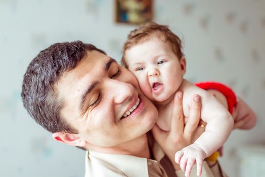 happy father holds on hands naked baby in a room