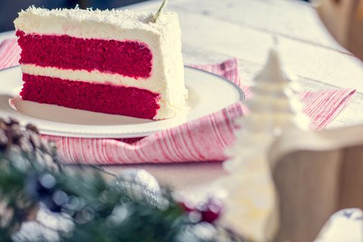 Christmas cake on plate on red fabric on wood background and decorations.