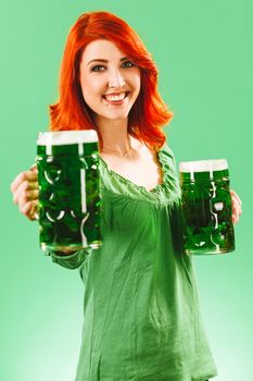 Photo of a beautiful redhead woman holding and drinking two huge green beers on St Patricks Day.