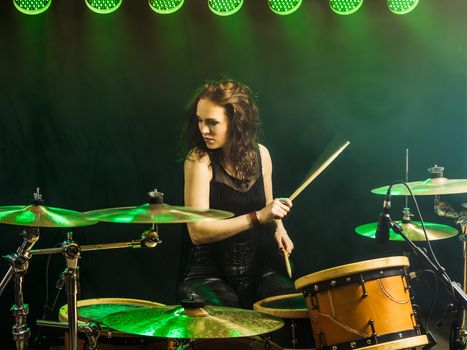 Photo of a beautiful woman playing her drum set on stage.