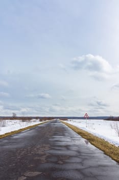 The photo shows a winter road in a field