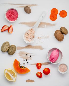 Homemade skin care and body scrubs with red natural ingredients strawberry , tomato ,himalayan salt,papaya, carrot and  stone on white wooden background with flat lay. Zen spa and oriental spa theme.