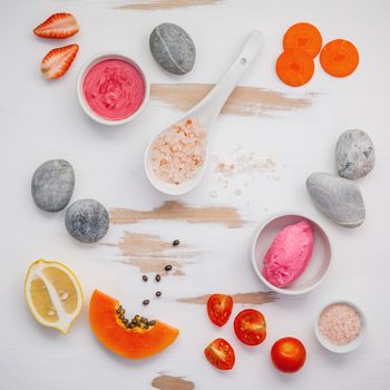 Homemade skin care and body scrubs with red natural ingredients strawberry , tomato ,himalayan salt,papaya, carrot and  stone on white wooden background with flat lay. Zen spa and oriental spa theme.