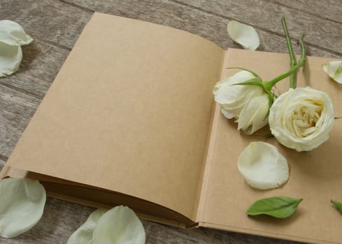 notebook with white rose on wooden table