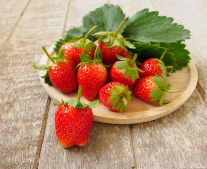 Strawberries from the garden that is placed on a wooden tray.