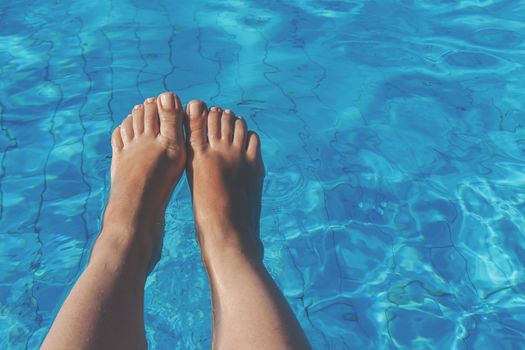 naked female legs on a background of blue water.