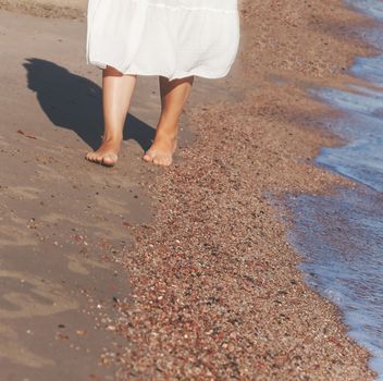 vacation travel - woman leg closeup walking on white sand relaxing in beach cover-up pareo beachwear. Sexy and tanned legs. Sunmmer holidays, weight loss or epilation, pedicure concept.