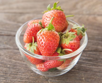 Strawberry in a glass on a wooden table.