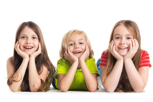 Happy smiling three children in colorful clothes laying on floor isolated on white background