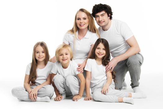 Studio portrait of family in white clothes with three children isolated on white background