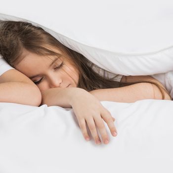 Beautiful girl sleeping in bed under white blanket