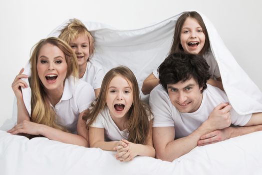 Smiling family with three children wake up in bed