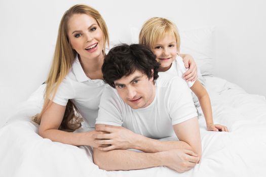 Smiling family with child wake up in bed