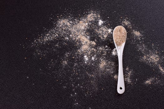 White whole-wheat flour and a spoon on a black background