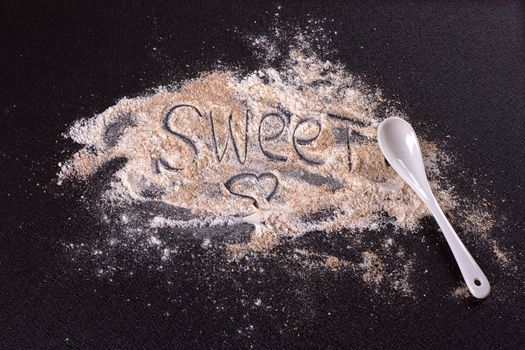 White whole-wheat flour and a spoon on a black background