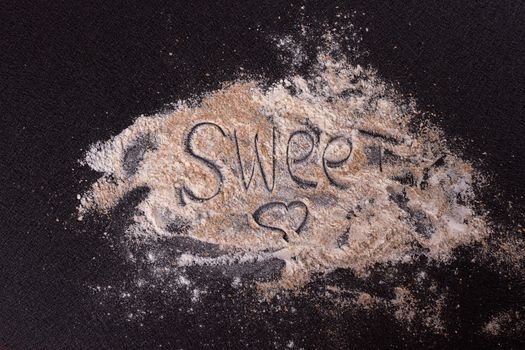 White whole-wheat flour and a spoon on a black background