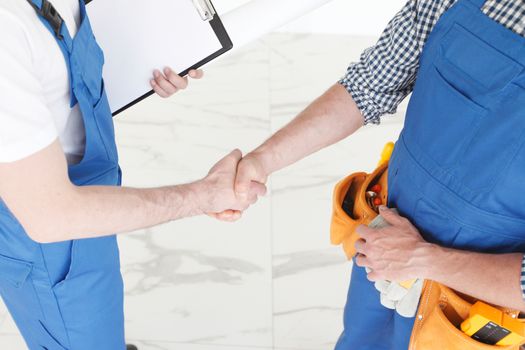 Two construction workers shaking hands, deal is finished concept