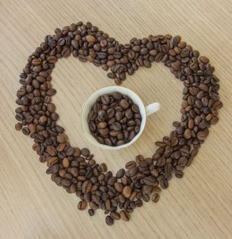 Morning heart. Heart shape made from coffee beans and a cup of coffee in center.