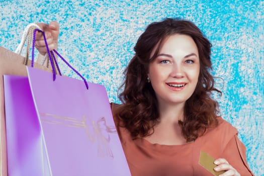 Happy smiling woman holding colourful shopping paper bags and banking credit card