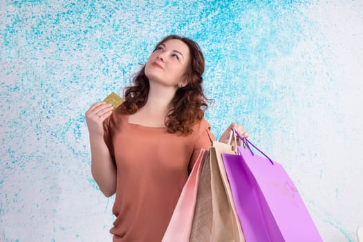 Happy smiling woman holding colourful shopping paper bags and banking credit card